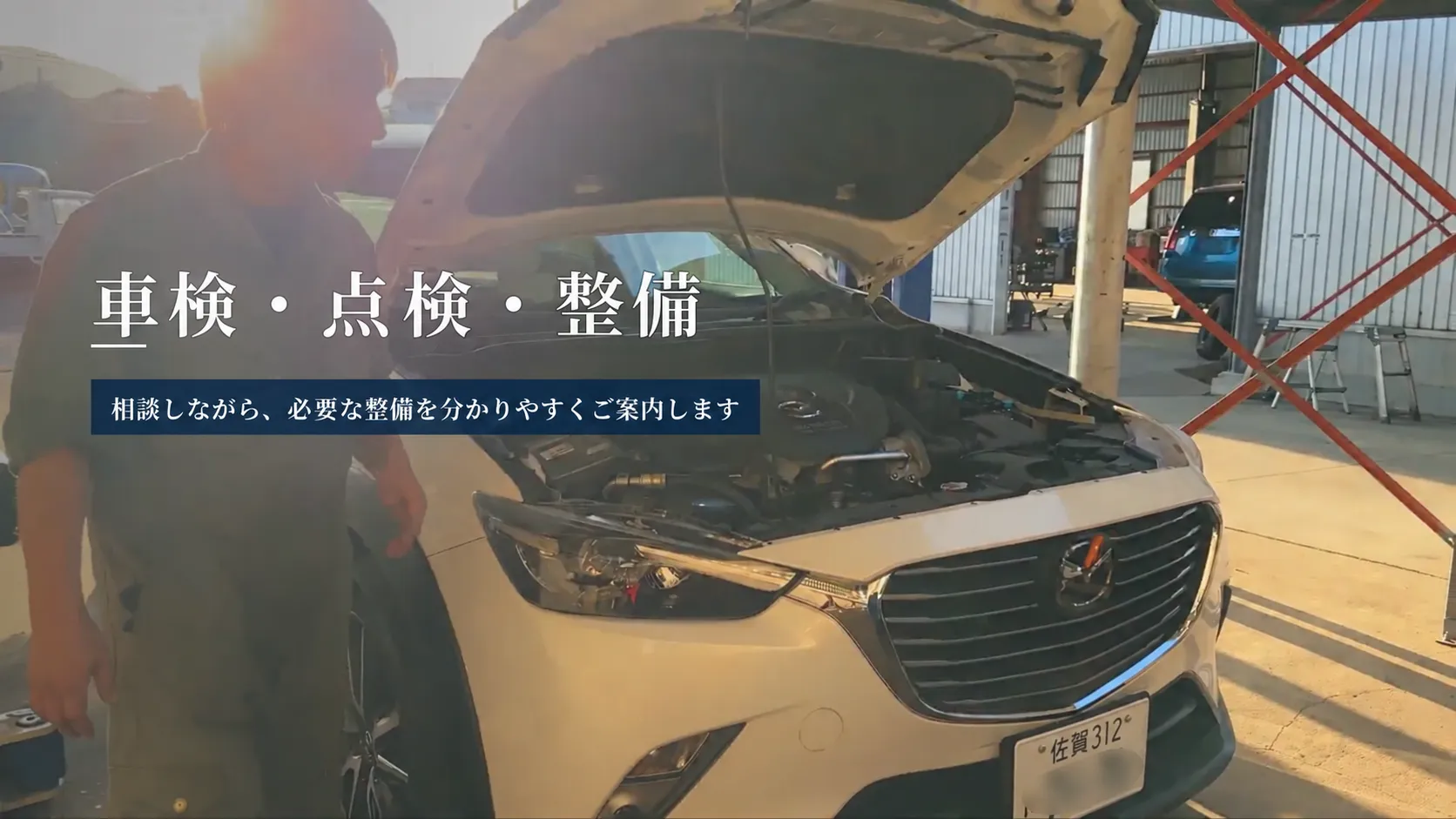 夕陽が差し込む整備工場で整備士がボンネットを開けた車を確認している車検・点検・一般整備の案内画像